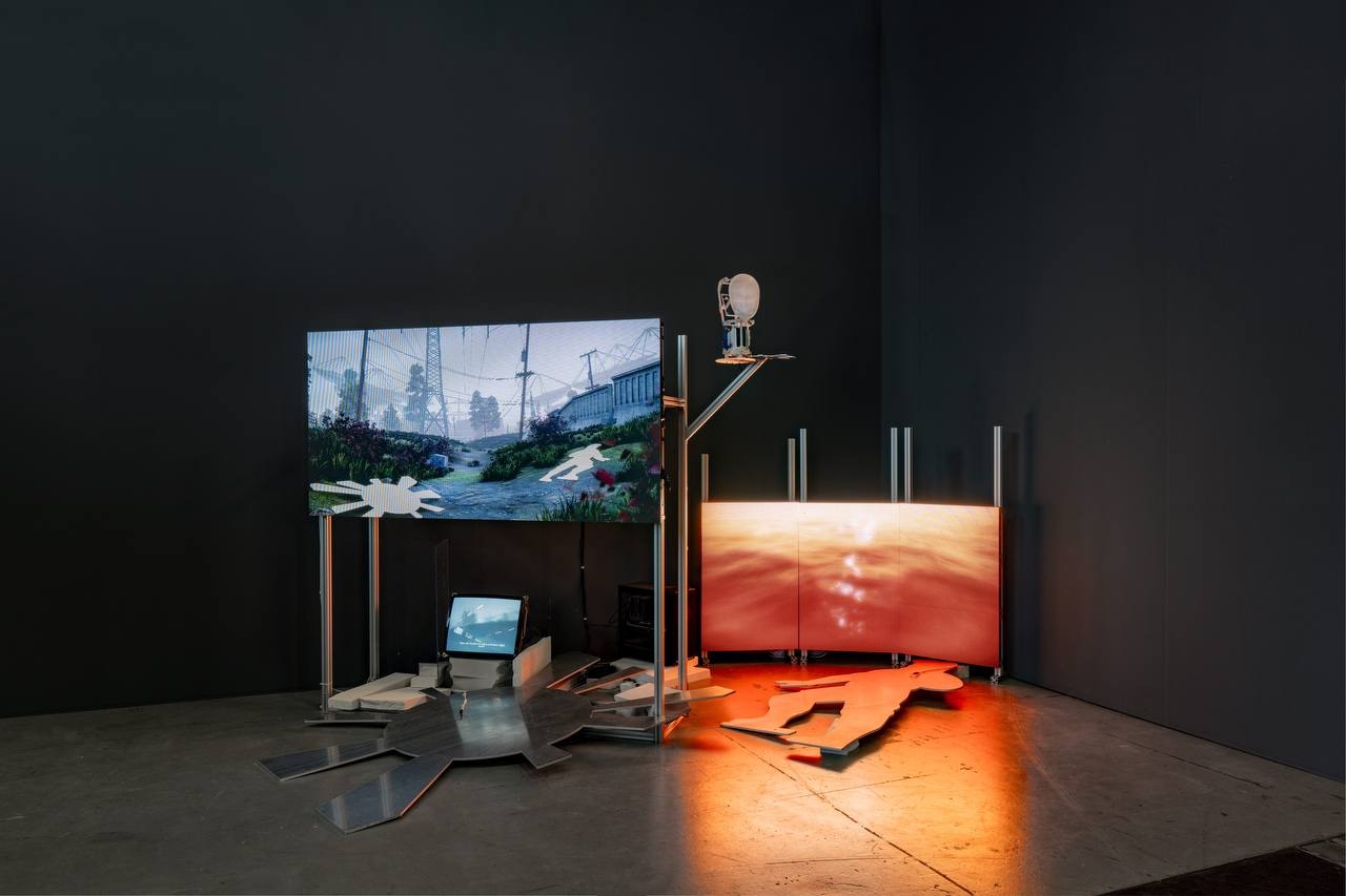 NewMan installation: screens and a mechanical face on a metal structure, lit by amber water imagery